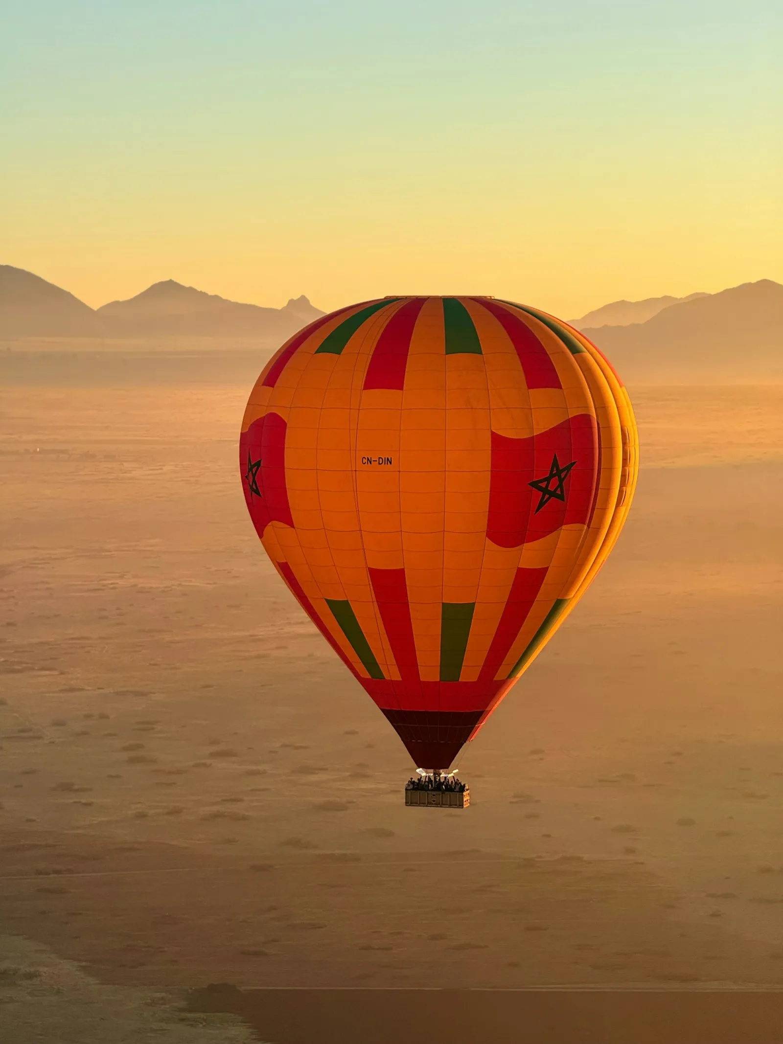 Montgolfière aux couleurs du Maroc au-dessus du désert au lever du soleil, près de Marrakech